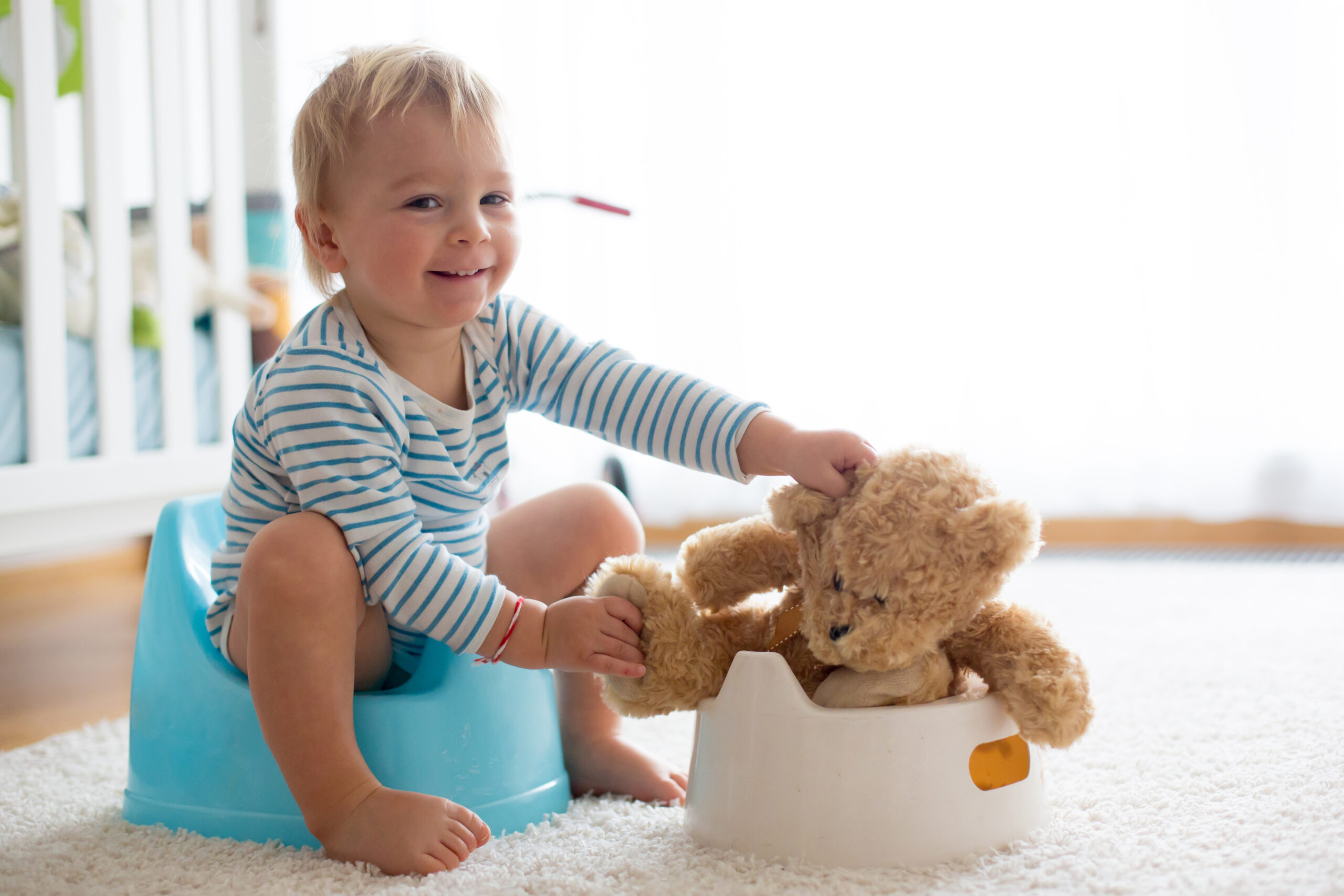 toddler on potty chair playing with bear